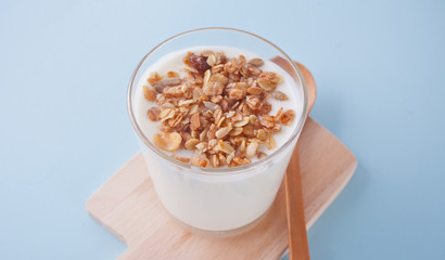 Granola with yogurt in glass on a blue table.