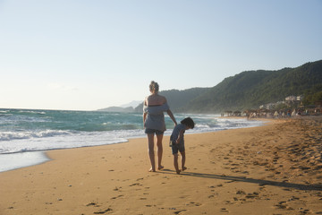 Mother and son playing on the sandy beach. Summer vacation concept, mom and little boy enjoy at beach