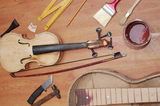 Handmade. Violin, guitar and hand tools on a wooden table brush, varnish, ruler, knife, hammer