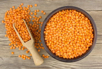 Red lentils  in plate and scoop on wooden background