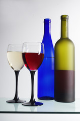 Two glasses of white and red wine and two bottles
