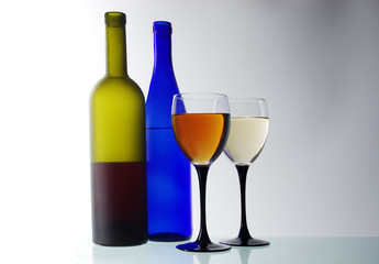 Two glasses of wine and two bottles on a light