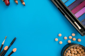 Top, up view of professional cosmetics, makeup background. Brushes, eye shadows, eyebrow pencils, powder, bronzing balls, mascara, red lipstick. Tools isolated on blue. Concept of get ready for party