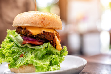 A plate of a beef  cheeseburger on wooden table in the restaurant