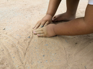 Hands child playing in the sand.