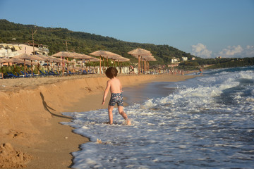 Child running and play at beach. Little boy play by the sea on summer vacation