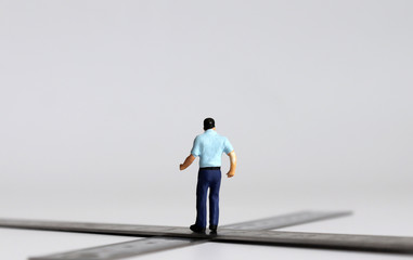 The back of a miniature man standing at a crossroads.
