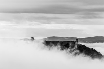 Obraz na płótnie Canvas A view of Rocca Maggiore castle in Assisi (Umbria, Italy) in the middle of fog