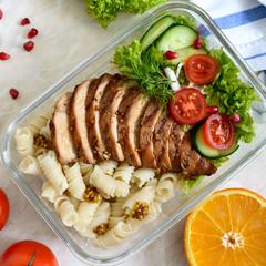 Lunch box: rotini with baked chicken breast and salad. Top view, flat lay. Delicious healthy lunch. The concept of healthy eating.