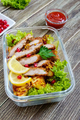 Warm salad of baked potatoes, meat, greens with spicy sauce in a glass bowl on a wooden table. Lunch box.