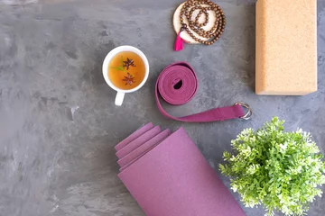 Papier Peint photo École de yoga Tapis de yoga enroulé avec des perles de mala et du thé ayurvédique pour une pratique relaxante du yoga et de la méditation.