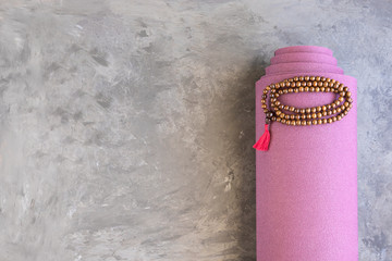 Rolled yoga mat and classic mala beads , essential things for yoga practice y meditation..Copy...