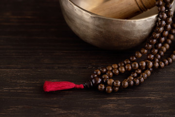 Tibetan singing bowl  with mala beads on dark wooden background with copy space. Essential...