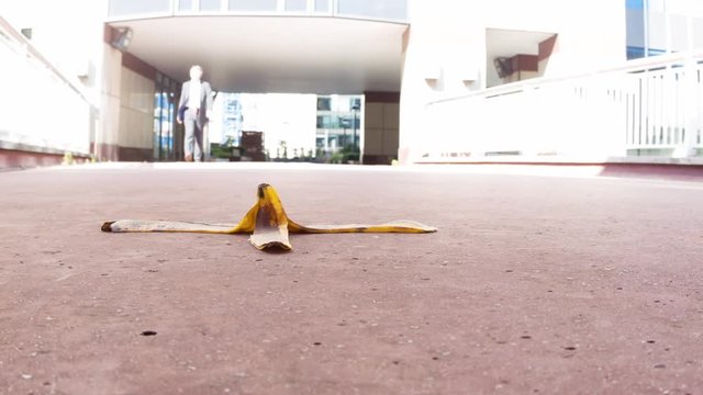 Low angle view of a caucasian businessman stepping over a banana skin themes of accident insurance danger careless