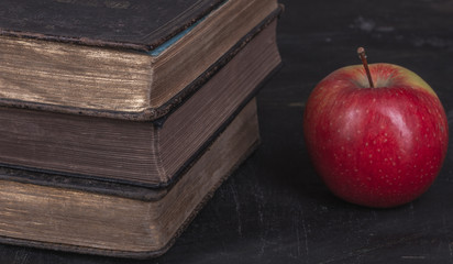 Bardzo stare i zabytkowe ksiazki , podreczniki szkolne i jablko czerwone.
