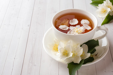 Mug of herbal tea with petals of Jasmine flowers on a light background.