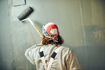 Painter painting walls with a extender roller indoors.