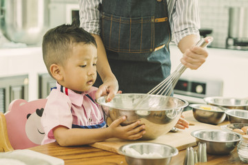 happy family in kitchen. mother and son knead dough and bake the bakery together