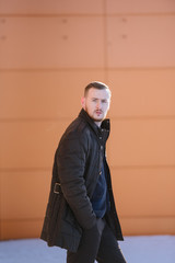 A man with a beard in a warm winter brown jacket poses for advertising of men's clothing in the winter. Advertising of men's clothing