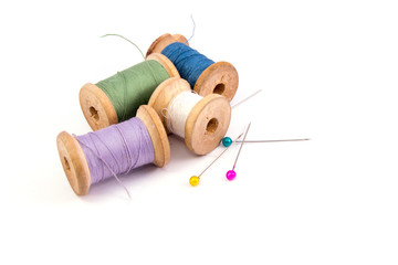 green blue purple white sewing threads and colored needles on white background isolated