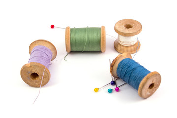 green blue purple white sewing threads and colored needles on white background isolated