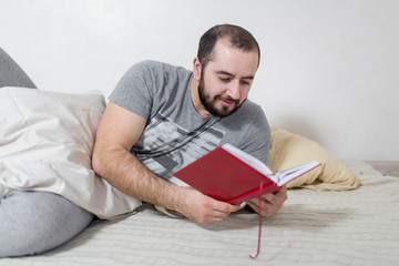 Young man reads a book in the bedroom. White background.