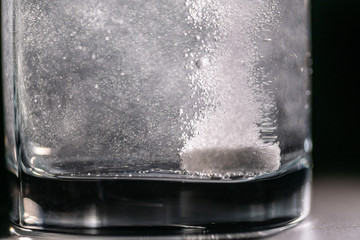 Tablet in glass with water on a black background