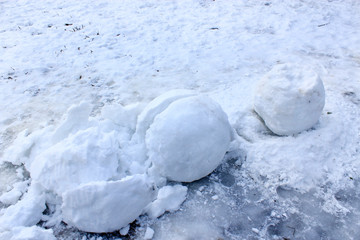 Broken balls of snow of which snowman was made are lying in snow