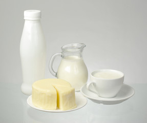   A jug of milk, a piece of cheese on a saucer 