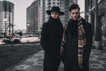 Two young stylish men posing on city street. Classic urban style. Street man model tests.