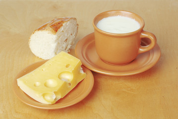 A cup of milk, a jug of milk, a piece of cheese