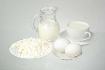 Milk in a white cup and jug, creative and eggs on a white background