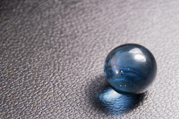 blue glass ball on black leather background