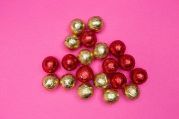 Chocolates in a multi-colored foil on a pink background