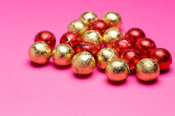 Chocolates in a multi-colored foil on a pink background