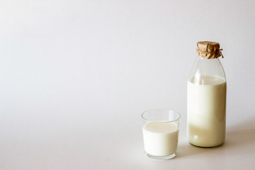A bottle and glass of milk on a grey background. Minimalism