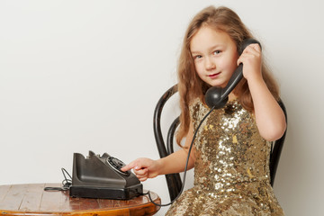 A little girl is ringing on the old phone.