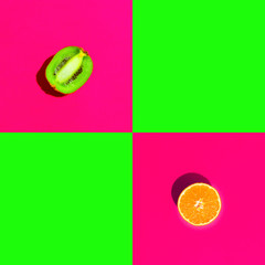 Ripe juicy halved orange kiwi on duotone bright neon fuchsia pink green background with blank...