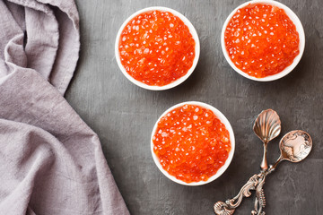 red salmon caviar in a plate on a dark table.