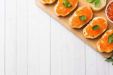 Sandwiches with red salmon caviar on a wooden Board. White table top.