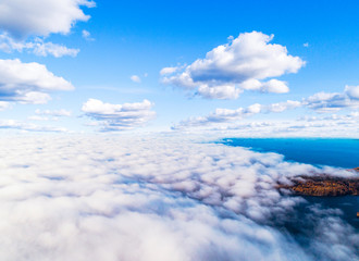 Fototapeta premium Aerial view over forest during vibrant autumn colors. Aerial view of seashore and clouds. Coastline with sand and water. Aerial drone view of forest. Aerial top view cloudscape. Texture of clouds.