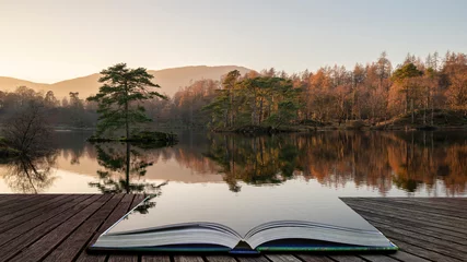 Wall murals Deep brown Beautiful landscape image of Tarn Hows in Lake District during beautiful Autumn Fall evening sunset with vibrant colours and still waters coming out of pages in magical story book