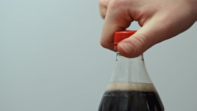Woman opening plastic delicious soda - cola bottle close up.