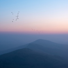 Stunning Winter sunrise landscape image of The Great Ridge in the Peak District in England with birds flying around the peaks