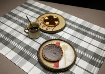 Schokoladen Tartelettes mit Kaffeetasse auf kariertem Tischtuch