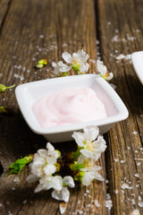 cosmetics and cherry blossom on old wooden table background