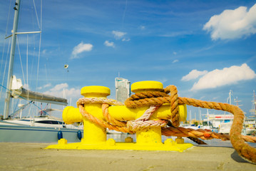 Sailing ropes tied around yellow marina bollard