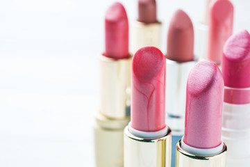 Obraz premium Set of colored pink lipsticks on white background. Women's cosmetics. Selective focus. Copy space.