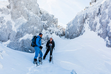 Wanders with trekking sticks rest under an icy rock.