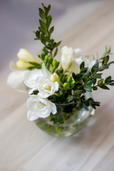 white freesia flowers in a round vase